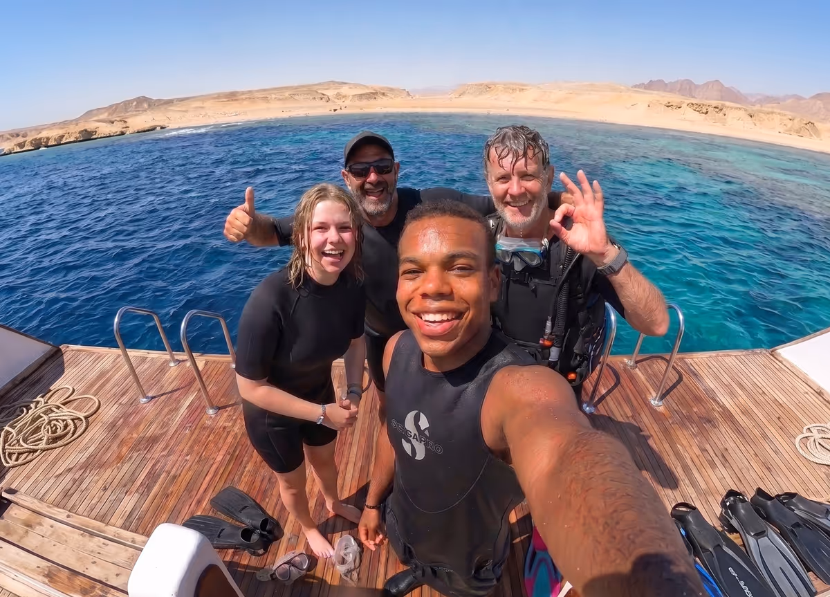 Four divers smiling on a DiveRED boat after a Red Sea day trip